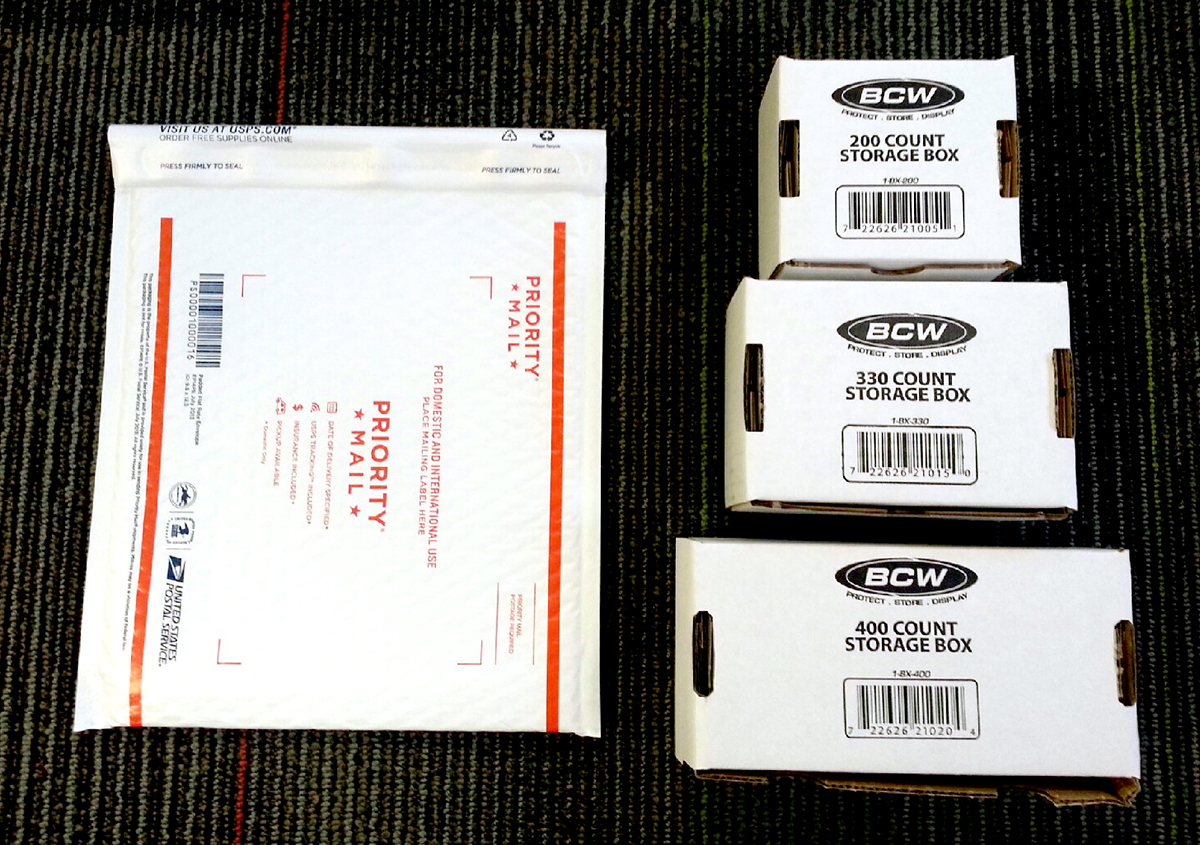 A USPS padded envelope next to varios sizes of BCW boxes.